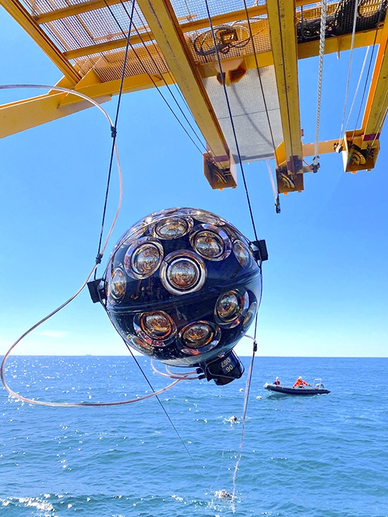 The KM3NeT DOM during a recovery operation. The two black ropes secure the 18 DOMs that form a single DU. The cable attached to the DOM is the VEOC, which supplies power and enables data transmission via fiber connection by KM3NeT, a next-generation neutrino observatory submerged up to 3,500 meters beneath the Mediterranean