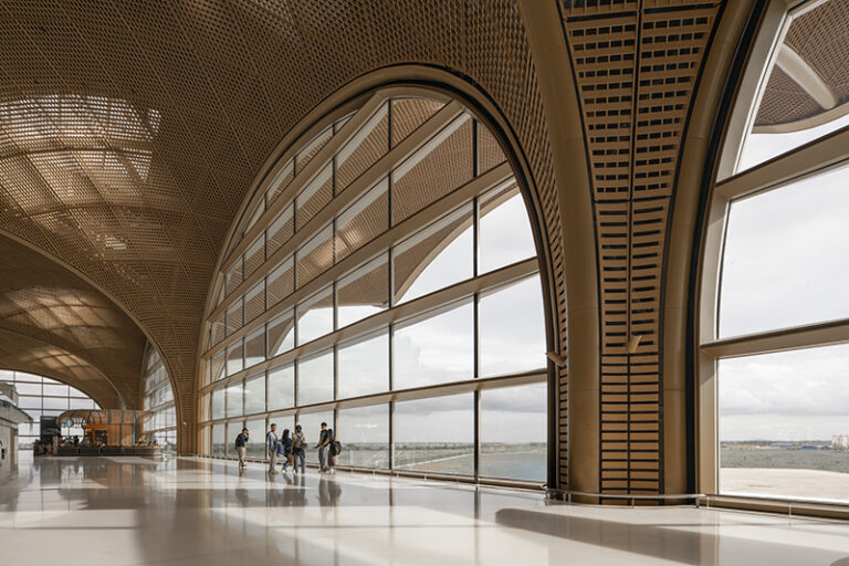 Short walking distances are prioritized throughout the terminal, with clear sightlines ensuring intuitive navigation. The basket-weaving-inspired latticed ceiling filters tropical sunlight while floor-to-ceiling windows maintain visual connections to the airfield.