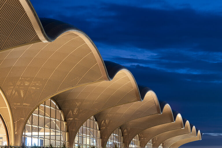 Foster + Partners tops Cambodian airport with latticed canopy. The undulating roof structure, inspired by traditional basket weaving and temple architecture, creates a dramatic silhouette against the evening sky while providing essential shading for the tropical climate.