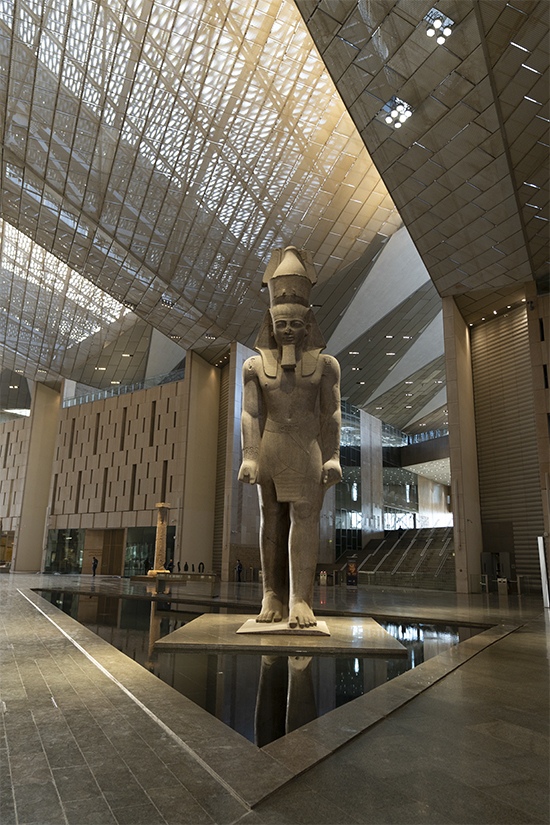 Front view of Ramesses II statue on a plinth above water inside the Grand Hall.