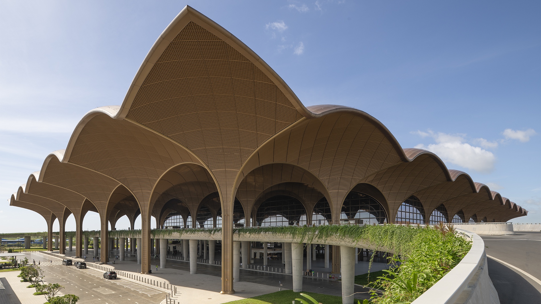 Steel columns expand into a vaulted roof at the Techo International Airport. The structural "trees" branch upward to support the modular canopy, which extends beyond the terminal to shade arrival areas and reduce heat gain in the tropical climate. Photography by Nigel Young.