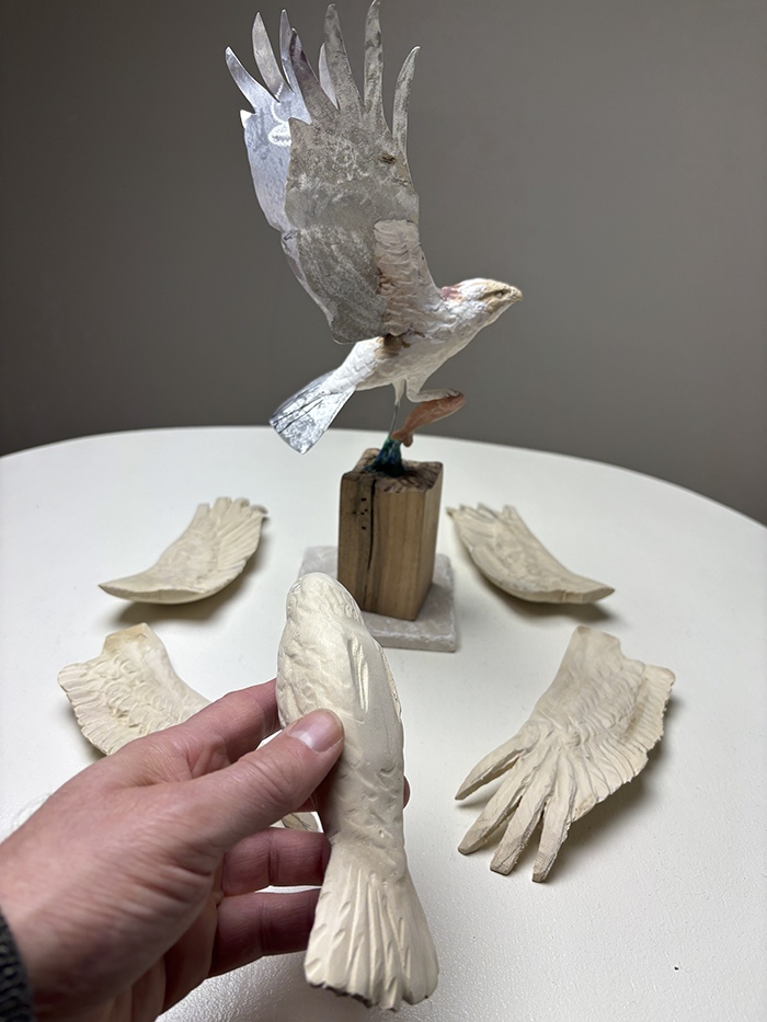 Separately carved osprey wings arranged around the sculpture before assembly
