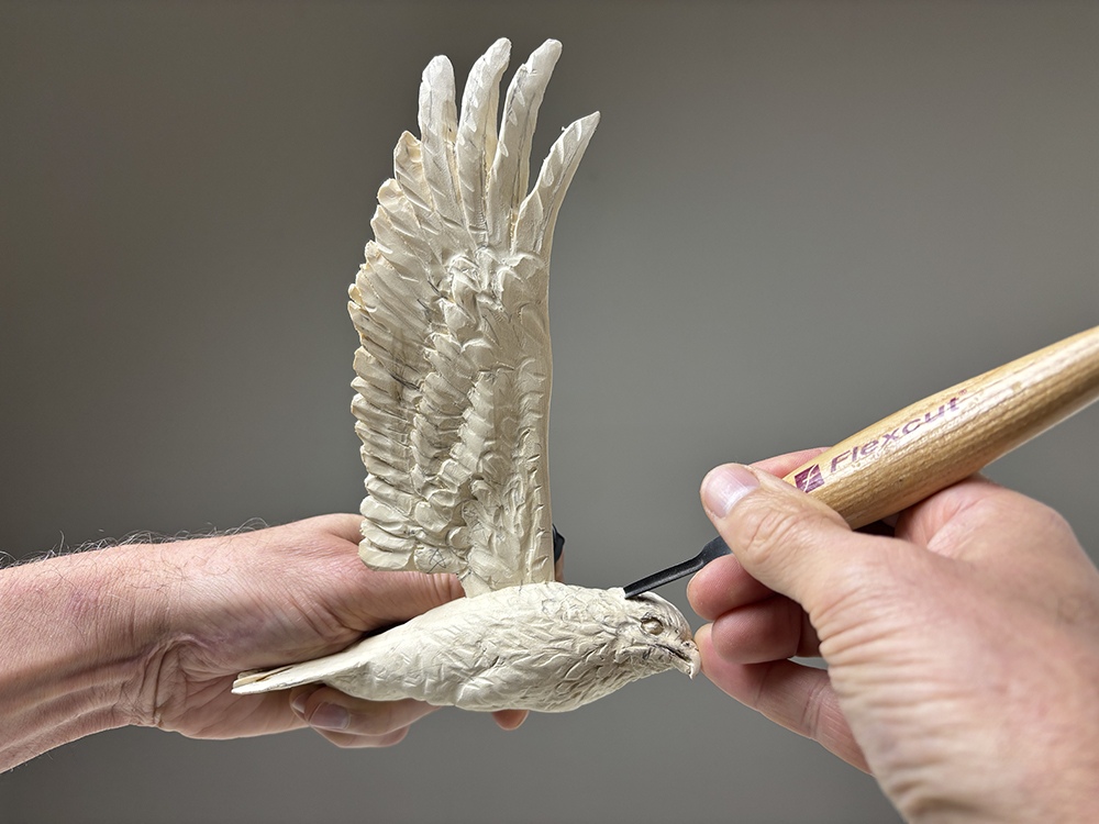 Individual feathers being carved and detailed into the wooden osprey wing