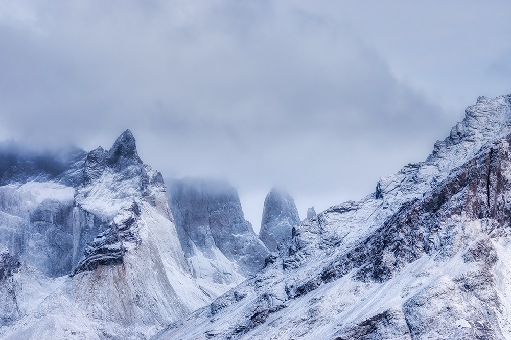 Snow and cloud obscure the summits of Torres del Paine, leaving only fragments of the peaks visible.