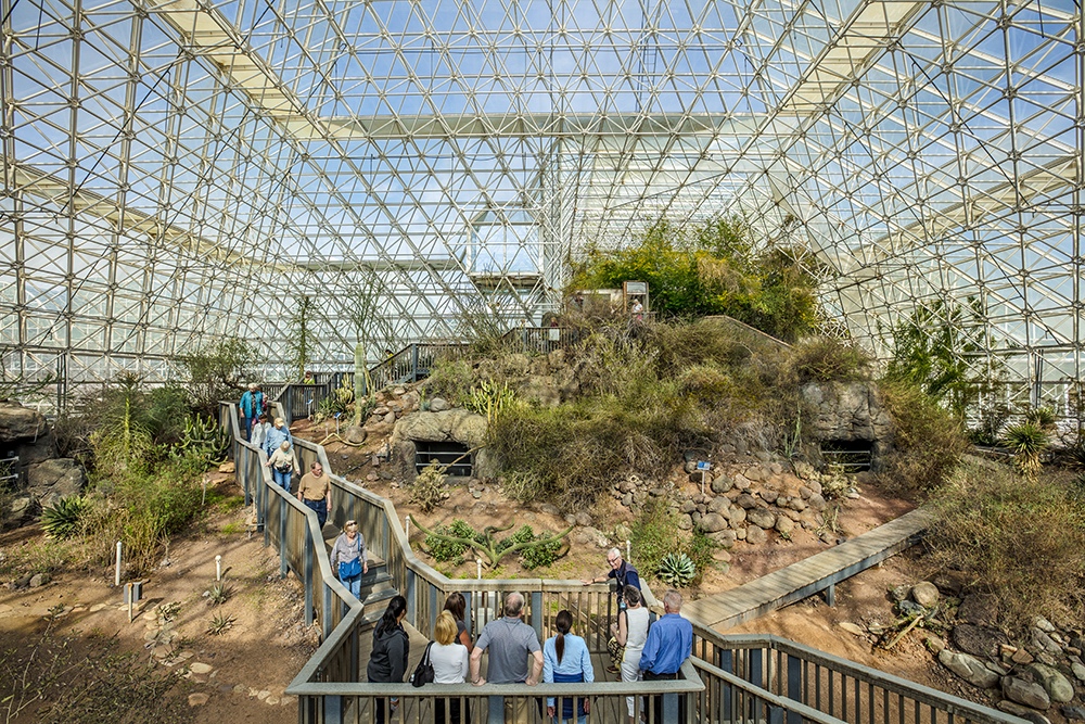 Visitors inside Biosphere 2 beneath the glass and steel frame